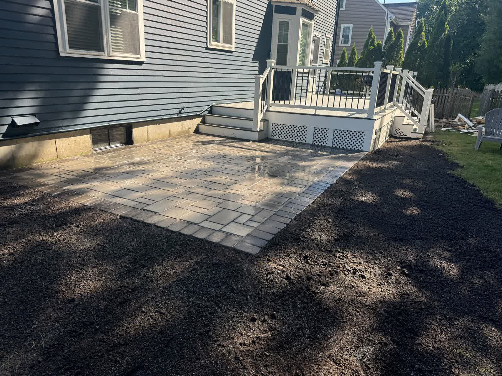 Paver patio with a seating area in a landscaped Massachusetts backyard