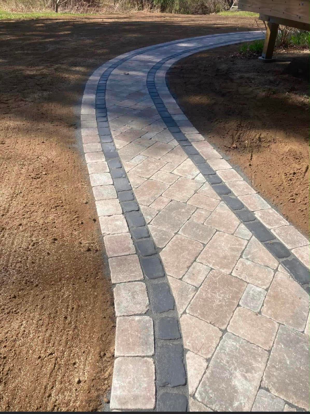 Curved paver walkway leading to a home entrance in a South Shore Massachusetts yard