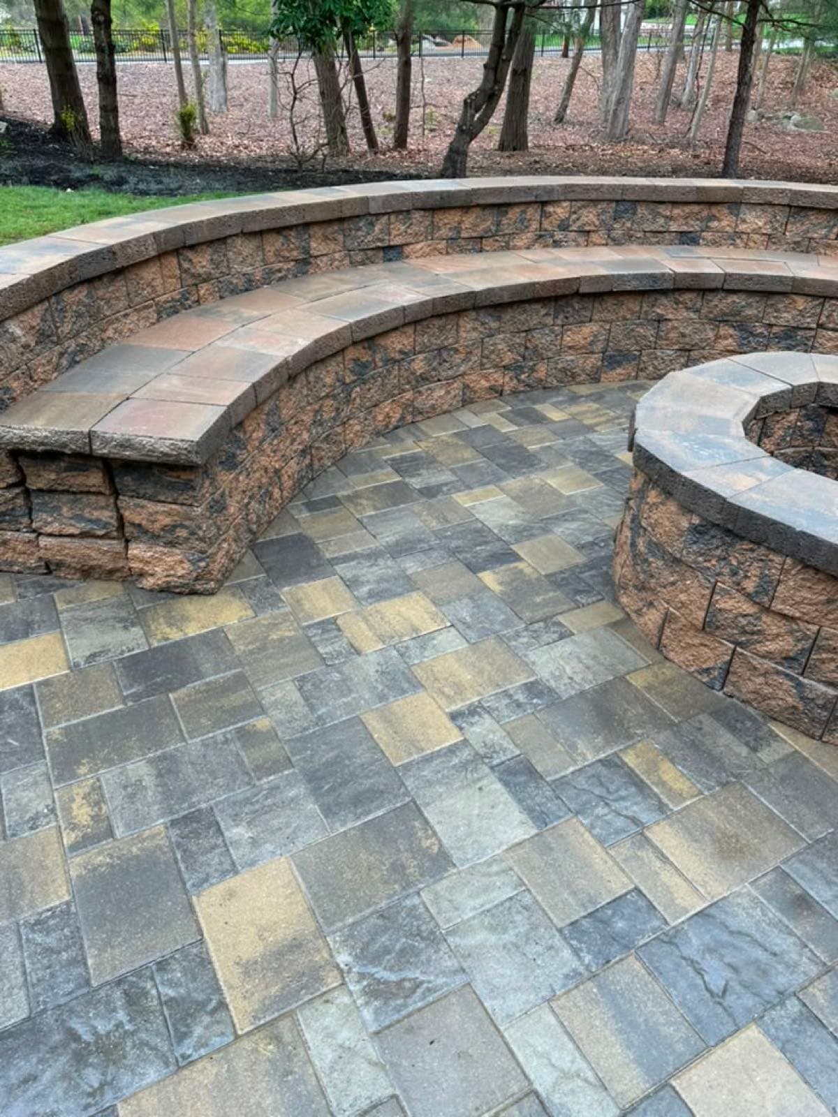 Finished paver patio with a fire pit and seating wall in a South Shore Massachusetts backyard