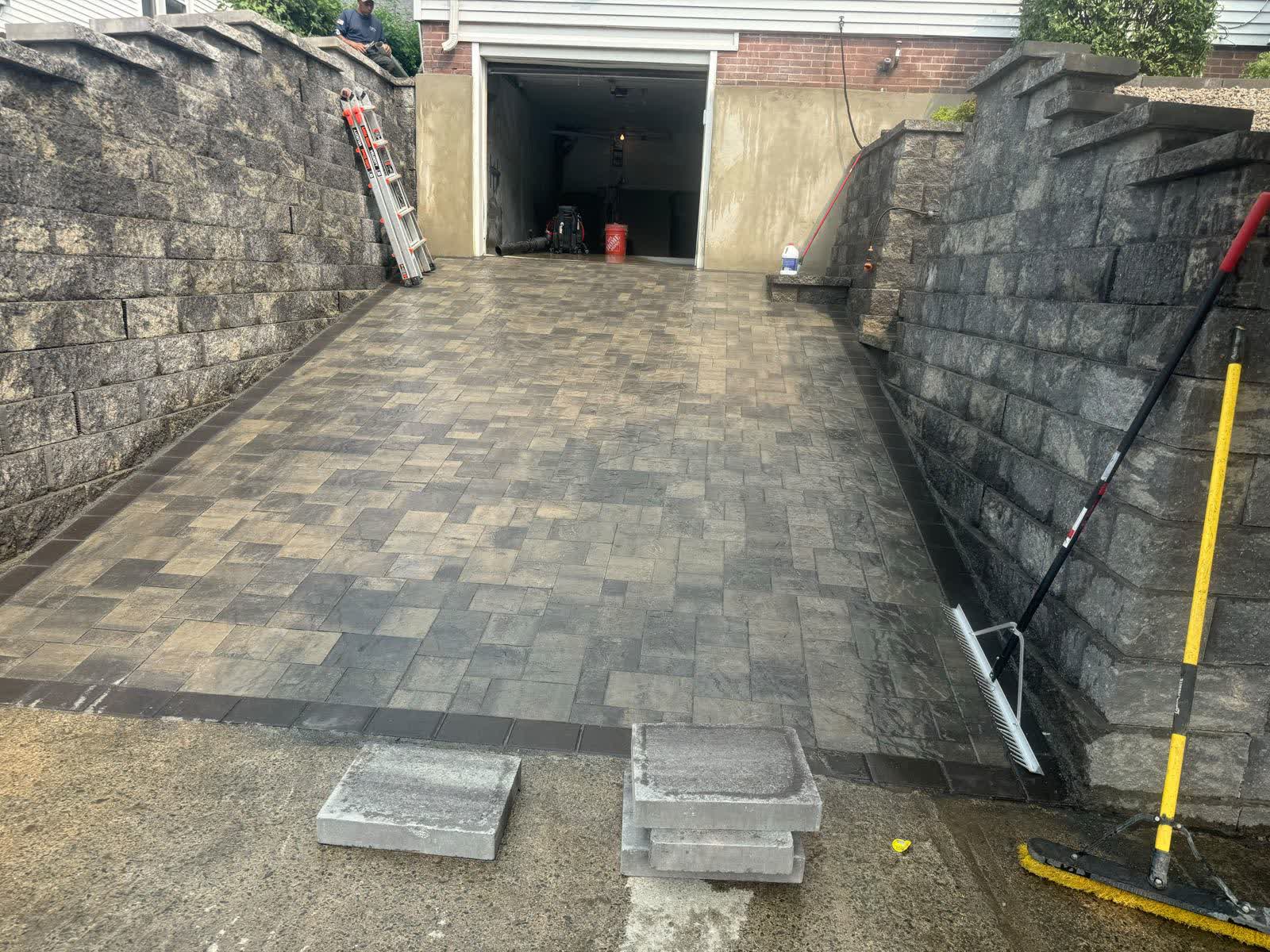 Paver driveway framed by charcoal block retaining walls