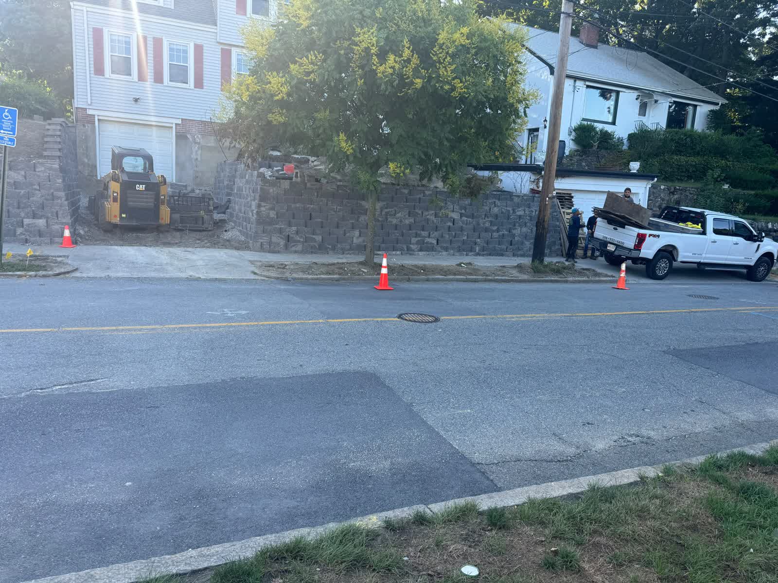 New charcoal block retaining wall built along the same street slope after the project